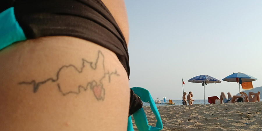 Tatuaggio dell'Isola d'Elba e la spiaggia di Lido sullo sfondo tatuaggio Elisa Capecchi